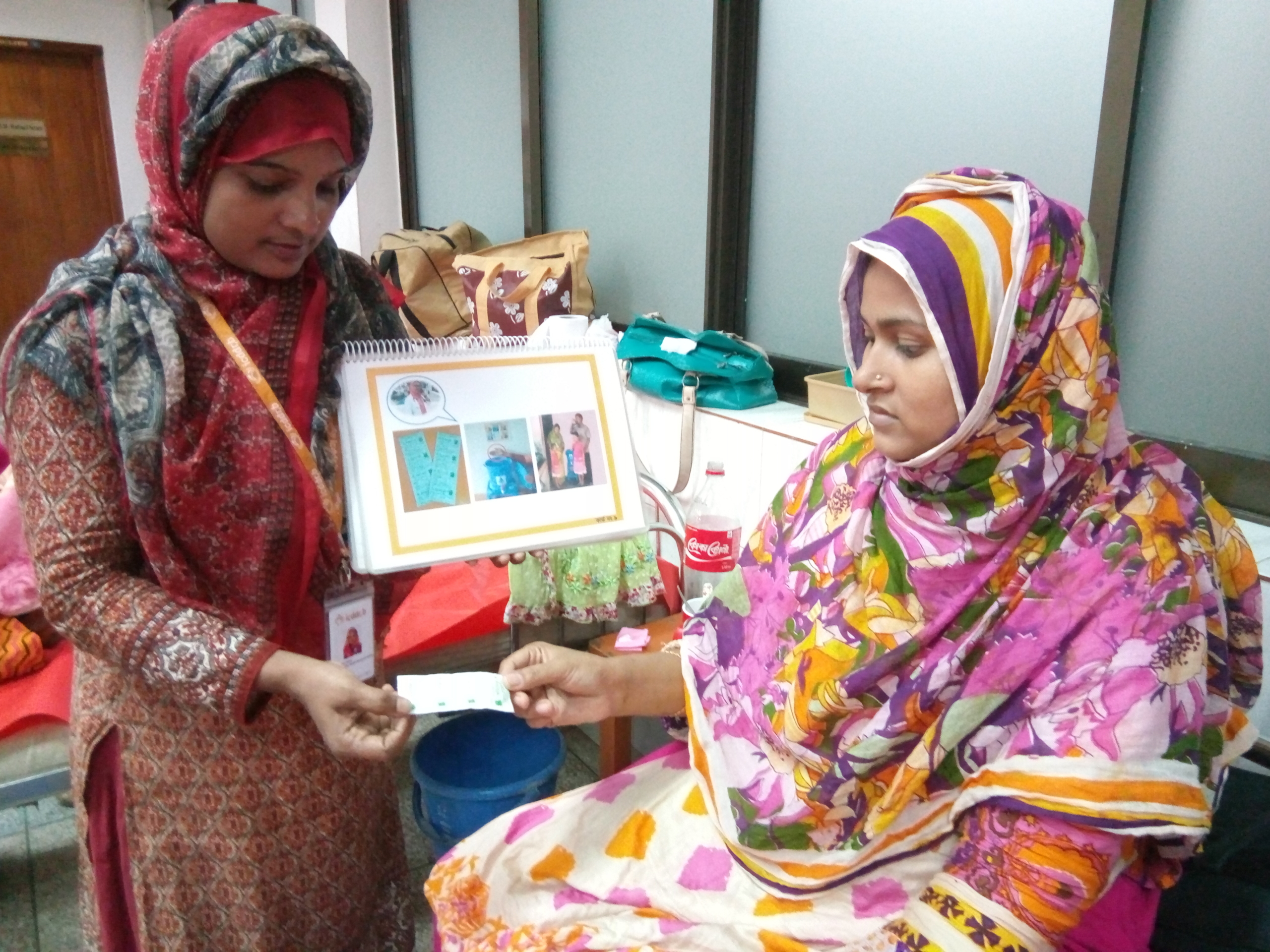 A health worker showing a mother educational materials during a home visit.