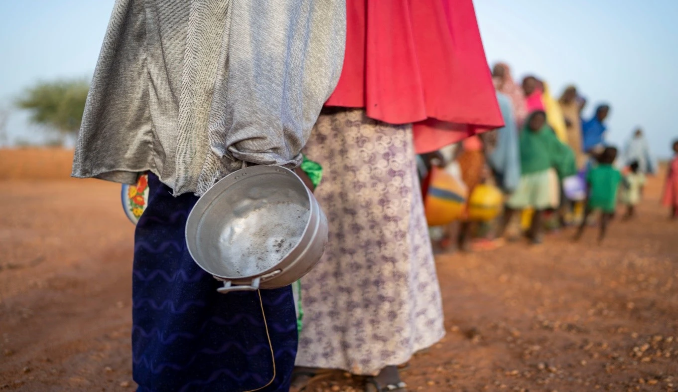 Long line for food rations, illustrating challenges in providing humanitarian aid and basic needs.
