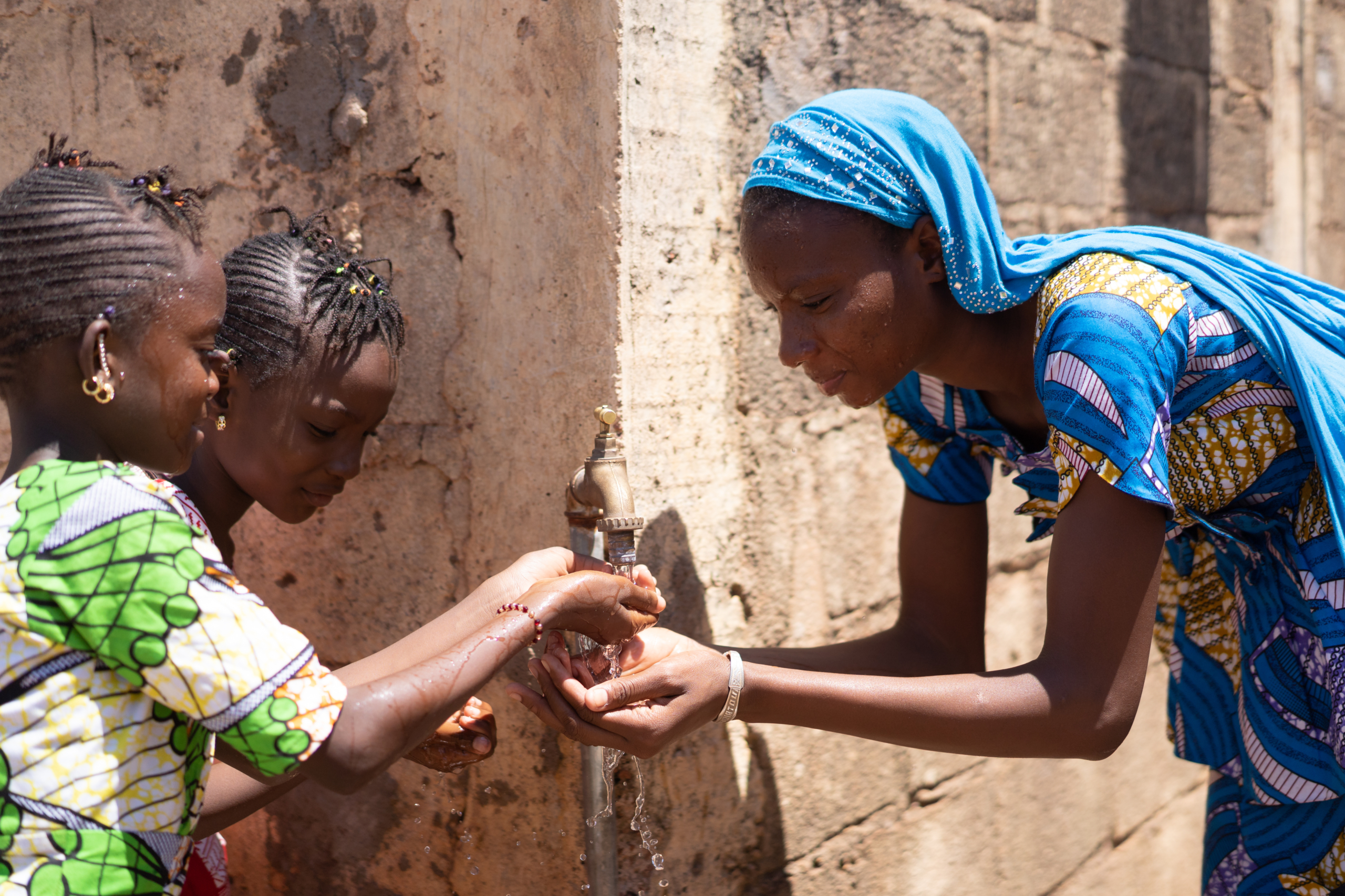 Children drinking clean water from a tap stand in South Sudan
